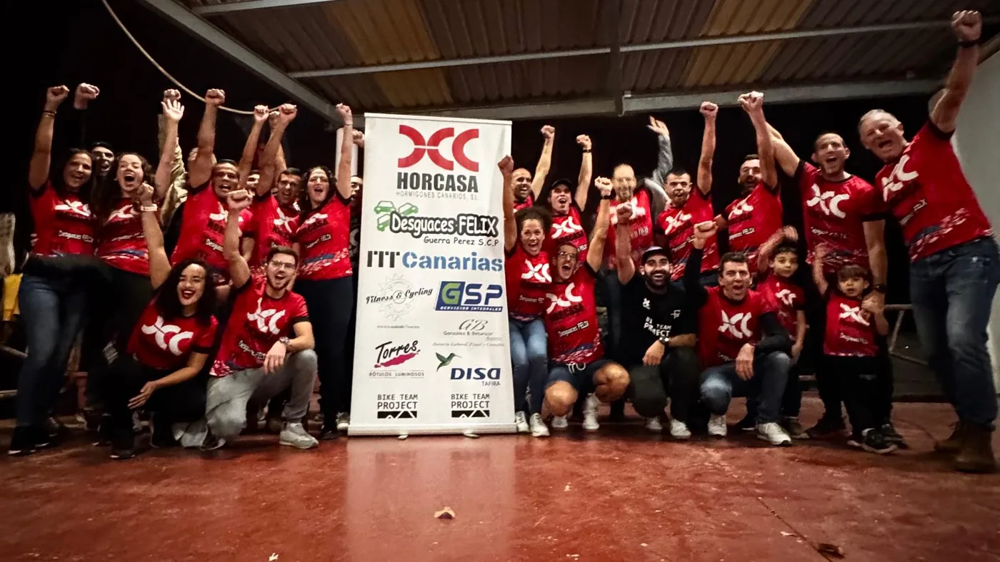 Fotografía de celebración colectiva en un encuentro deportivo con cartel de patrocinadores